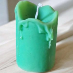 Petite bougie artisanale en cire de colza végétale faite à la main, avec mèche en coton, posée sur une coupelle décorative