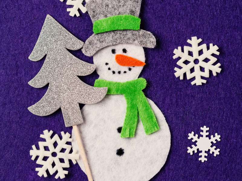 Écharpe en feutrine nouée autour du bonhomme de neige fabriqué en rouleau cartonné.