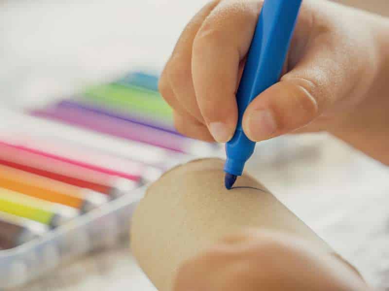 Visage de bonhomme de neige dessiné au feutre sur un rouleau peint en blanc<br />
