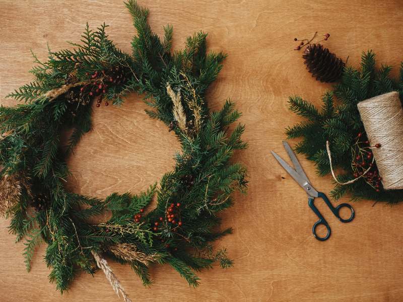 Matériel pour réaliser une couronne de Noël naturelle : cercle, feuillages, ficelle, décorations boisées